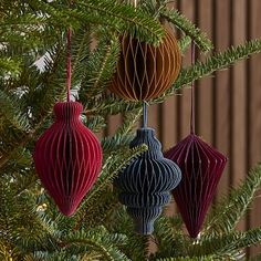 three ornaments hanging from a christmas tree with the words west elm written below them in black