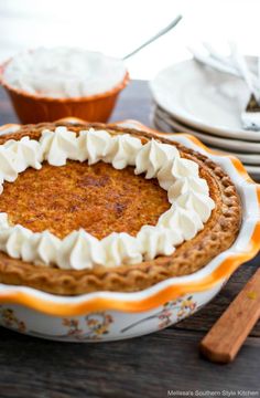 a pie sitting on top of a wooden table next to plates and utensils