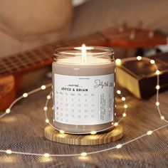 a candle with a calendar on it sitting next to a guitar and some string lights