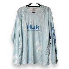 a blue shirt with the words huk on it hanging from a hanger in front of a white wall