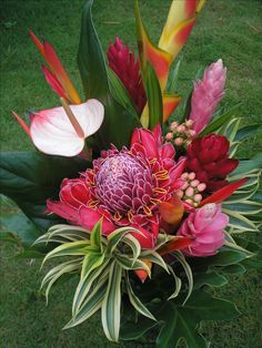 a vase filled with lots of colorful flowers on top of a grass covered field next to trees