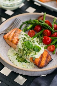 a plate with salmon, asparagus and tomatoes on it