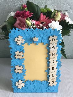 a blue and white frame with flowers in the center that says daniels spelled by scrabbles