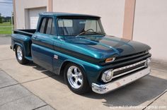 an old blue pickup truck parked in front of a building