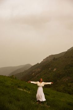 a woman standing on top of a lush green hillside