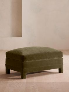 a footstool sitting on top of a hard wood floor next to a wall