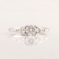 three stone diamond ring with reflection on white surface