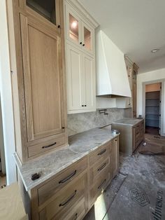 an unfinished kitchen with white cabinets and marble counter tops in the process of remodeling