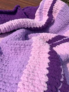 a purple and white crocheted blanket laying on top of a wooden floor