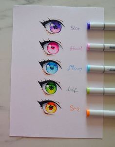 four different colored eyes on top of a piece of paper with markers next to them