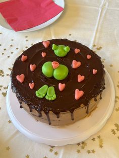 a chocolate cake with green and pink hearts on it sitting on a white tablecloth