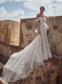 a woman in a wedding dress leaning against a stone wall