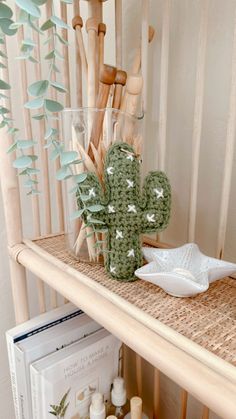 a shelf filled with candles and vases sitting on top of a wooden table next to a cactus