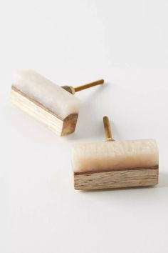 a pair of wooden and marble cufflinks on a white surface with one piece missing