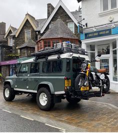 an suv parked in front of a building with a motorcycle on the back