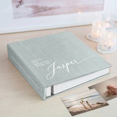 an open book sitting on top of a wooden table next to candles and other items