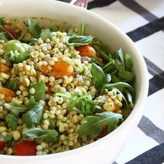 a white bowl filled with lots of food on top of a checkered table cloth