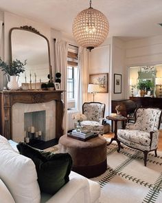 a living room filled with furniture and a fire place in front of a mirror on the wall