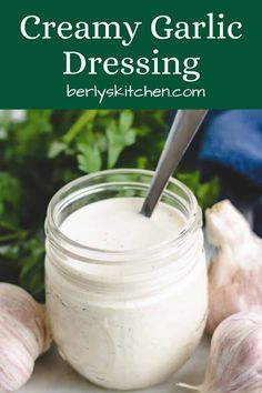 creamy garlic dressing in a jar with fresh herbs around it