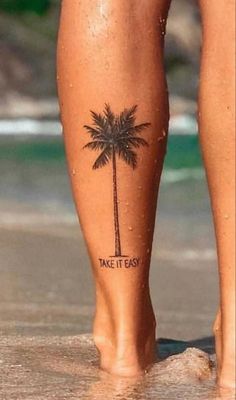 a person with a palm tree tattoo on their leg, standing in the water at the beach