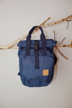 a blue bag hanging from a branch on a white wall next to some twig