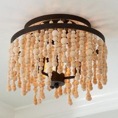 a chandelier made out of wooden beads hanging from the ceiling in a living room