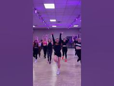 a group of women dancing in a dance studio with their arms up and hands in the air