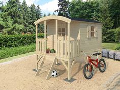 a child's play house with a bicycle parked in the sand