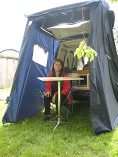 a woman sitting at a table in the back of a van with its door open