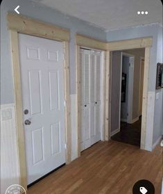 an empty living room with wood floors and white doors