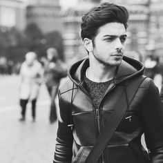 black and white photograph of a man walking down the street wearing a hoodie with his hands in his pockets