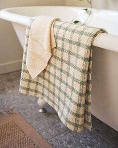 a white bath tub sitting next to a green checkered towel on top of it