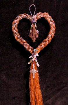 a heart shaped decoration hanging from a string with tassels in the shape of a cross