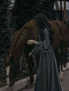 a woman standing next to a brown horse