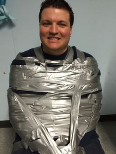 a man sitting on the floor wearing an inflatable silver piece of metal covering his face