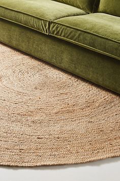 a green couch sitting on top of a wooden floor next to a large round rug