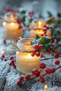 some candles are sitting in the snow with holly and berries around them on a table