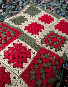 a crocheted blanket with red and green flowers on it