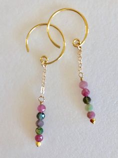 "Beautiful delicate faceted rainbow tourmaline dangles wire wrapped in gold on 24k gold vermeil ear wires. Natural 3.5-4 mm faceted rainbow tourmaline gemstones in shades of pink green and black. Gemstones are wire wrapped on delicate 24k gold fill chains which hang from petite 24k gold vermeil open circle ear wires. Total drop is 2 1/8\". Matching birthstone necklace also available in my shop. Please see last photo above. This listing is for earrings only. Also available in Sterling silver. Lov Handmade Gold Tourmaline Earrings, Gold Tourmaline Drop Earrings, Yellow Gold Tourmaline Dangle Earrings, Yellow Gold Tourmaline Dangle Jewelry, Gold Tourmaline Dangle Jewelry, Black Gemstones, Rainbow Tourmaline, Red Garnet Earrings, Tourmaline Earrings