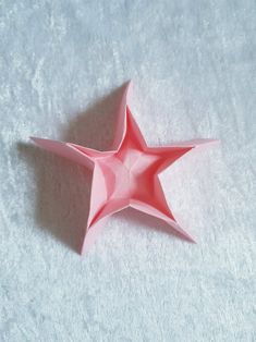 a pink origami star on a white surface