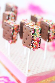 chocolate ice cream pops with sprinkles are on a pink and white tablecloth