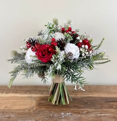 a bouquet of red and white flowers sitting on top of a wooden table