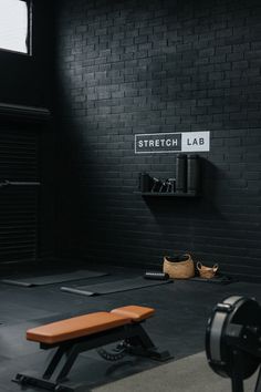 an empty gym room with black brick walls and flooring, including a weight bench