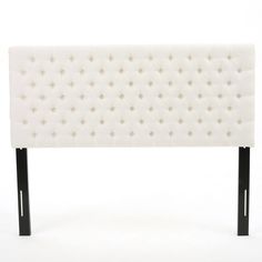 an upholstered white headboard with black legs and studded buttons on it