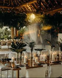 a long table with white chairs and candles