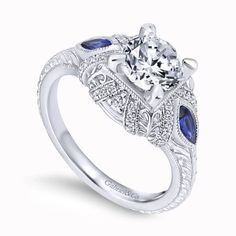 Celebrate timeless romance with the Gabriel "Lexington" Vintage Style Diamond and Blue Sapphire Halo Diamond Engagement Ring. This exquisite ring features 0.15 carats of round-cut diamonds and 0.40 carats of marquise-cut blue sapphires, forming a captivating halo. Milgrain details add a touch of vintage charm to the design. Meticulously crafted by Gabriel, this engagement ring is a radiant expression of sophistication and enduring love. Center diamond & wedding band sold separately Available in 14K or 18K white, rose or yellow gold, platinum, and palladium Includes ring box Includes jewelry appraisal Ships fully insured to point of delivery All rings are fully customizable by Gabriel should you prefer slight or major changes to the style you see. Alteration possibilities include alternate Blue Sapphire Engagement Ring Halo, Kirk Kara Engagement Rings, Sapphire Halo Engagement Ring, Gabriel Jewelry, Black Friday Jewelry, Gemstone Earrings Gold, Bridesmaid Gifts Jewelry, Silver Pearl Necklace, Gold Gemstone Ring