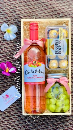 a bottle of gin and some candies in a box on the ground with flowers