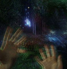 two hands reaching out to each other in front of a forest with trees and stars