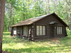 a log cabin in the woods with grass and trees