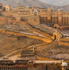 an aerial view of a large building in the middle of a desert area with mountains in the background